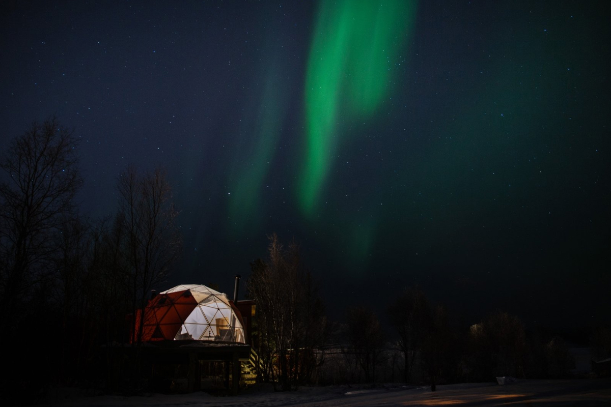 Aurora Igloo at Aera in Tromso, lit from within under the northern lights.