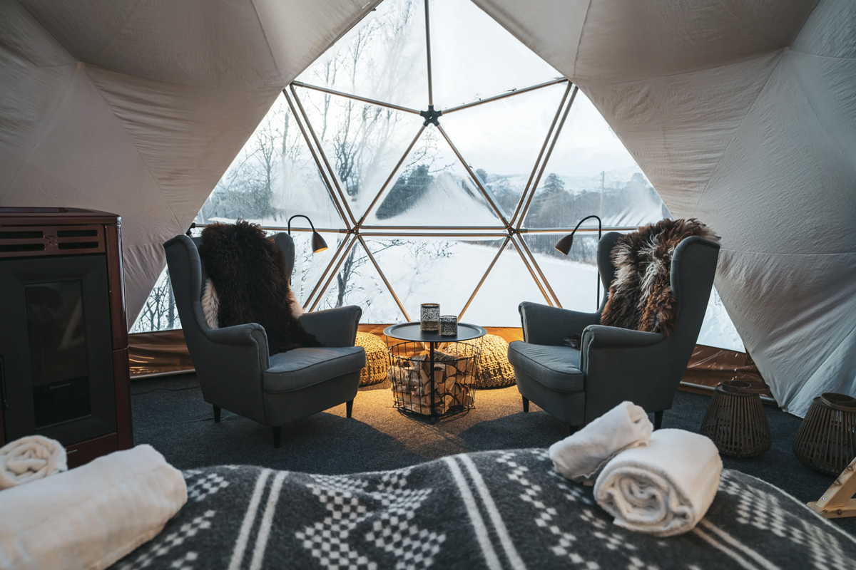 Aurora Igloo interior at Aera in Tromso, with armchairs by the fire.