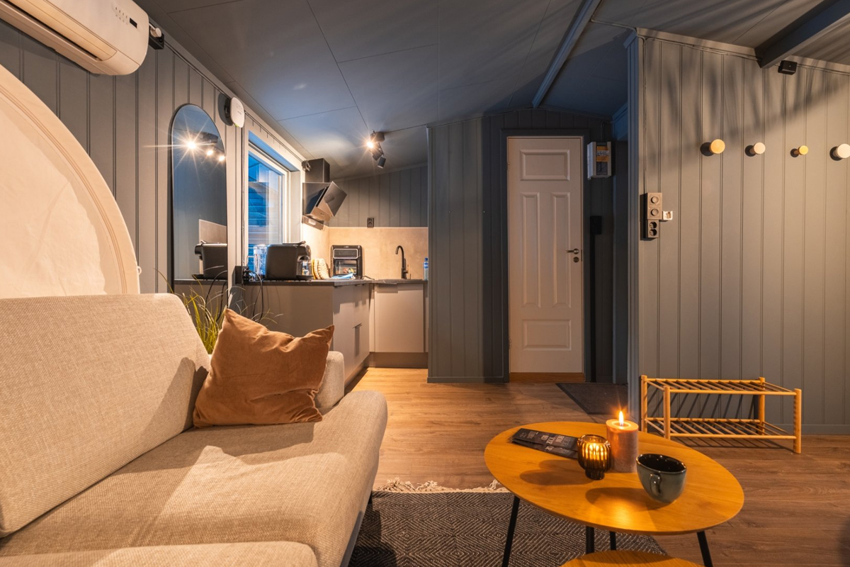 Sofa and kitchenette inside a cabin at Aera in Tromso.