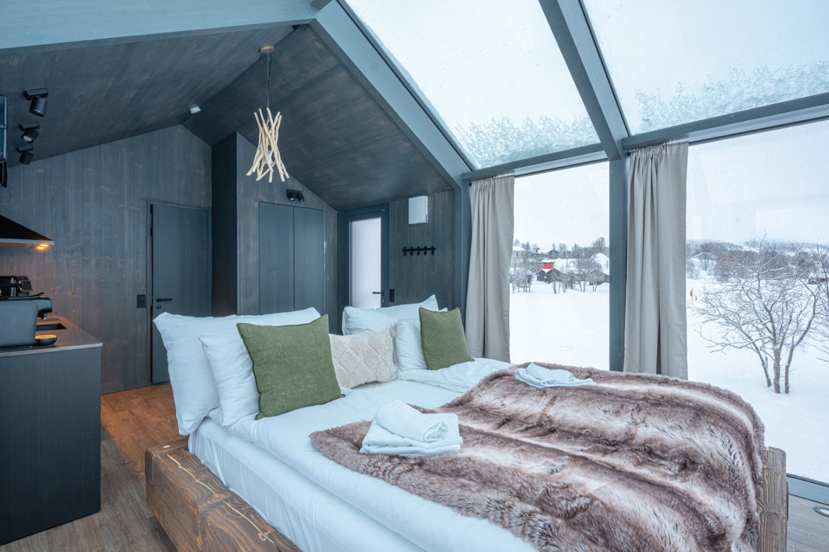 Bedroom inside a Panorama Glass Lodge at Aera, with glass gable and snow view.
