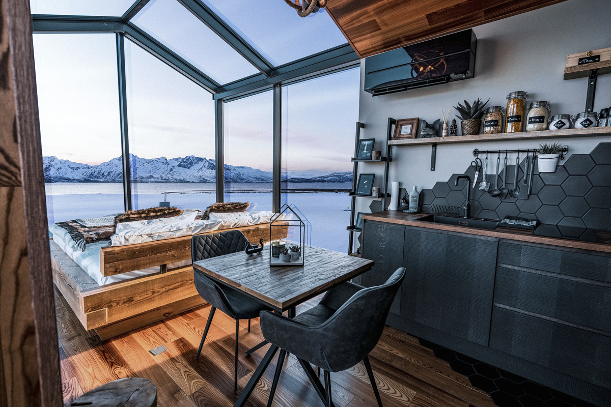 Kitchen and bed area inside a Panorama Glass Lodge at Aera, with water view.