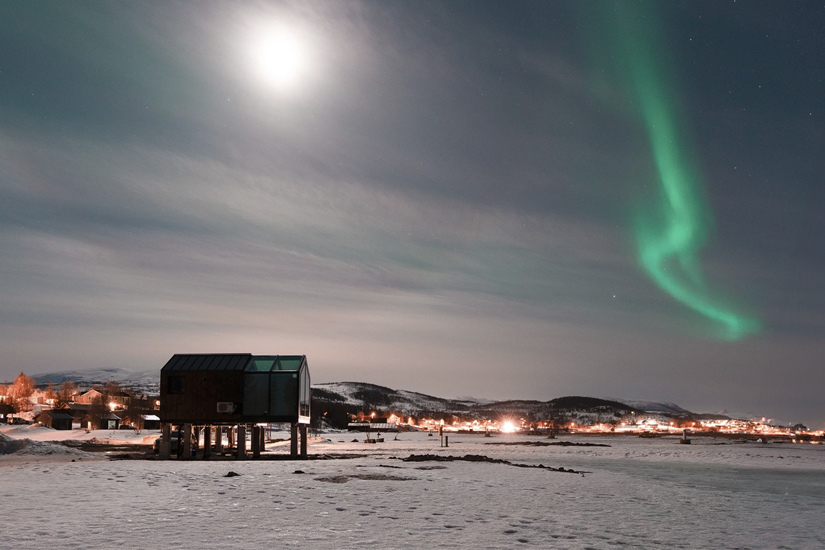 Panorama Glass Lodge at Aera in Tromso, with northern lights overhead.