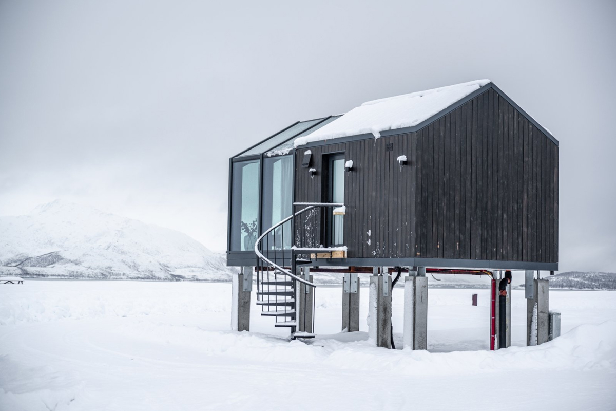 Panorama Glass Lodge at Aera in Tromso, raised above a frozen fjord.