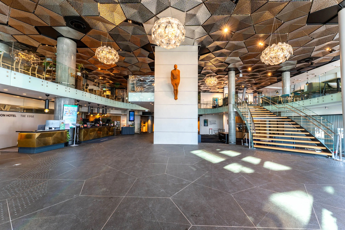 The front desk area beneath a geometric ceiling design at Clarion Hotel The Edge, Tromso.
