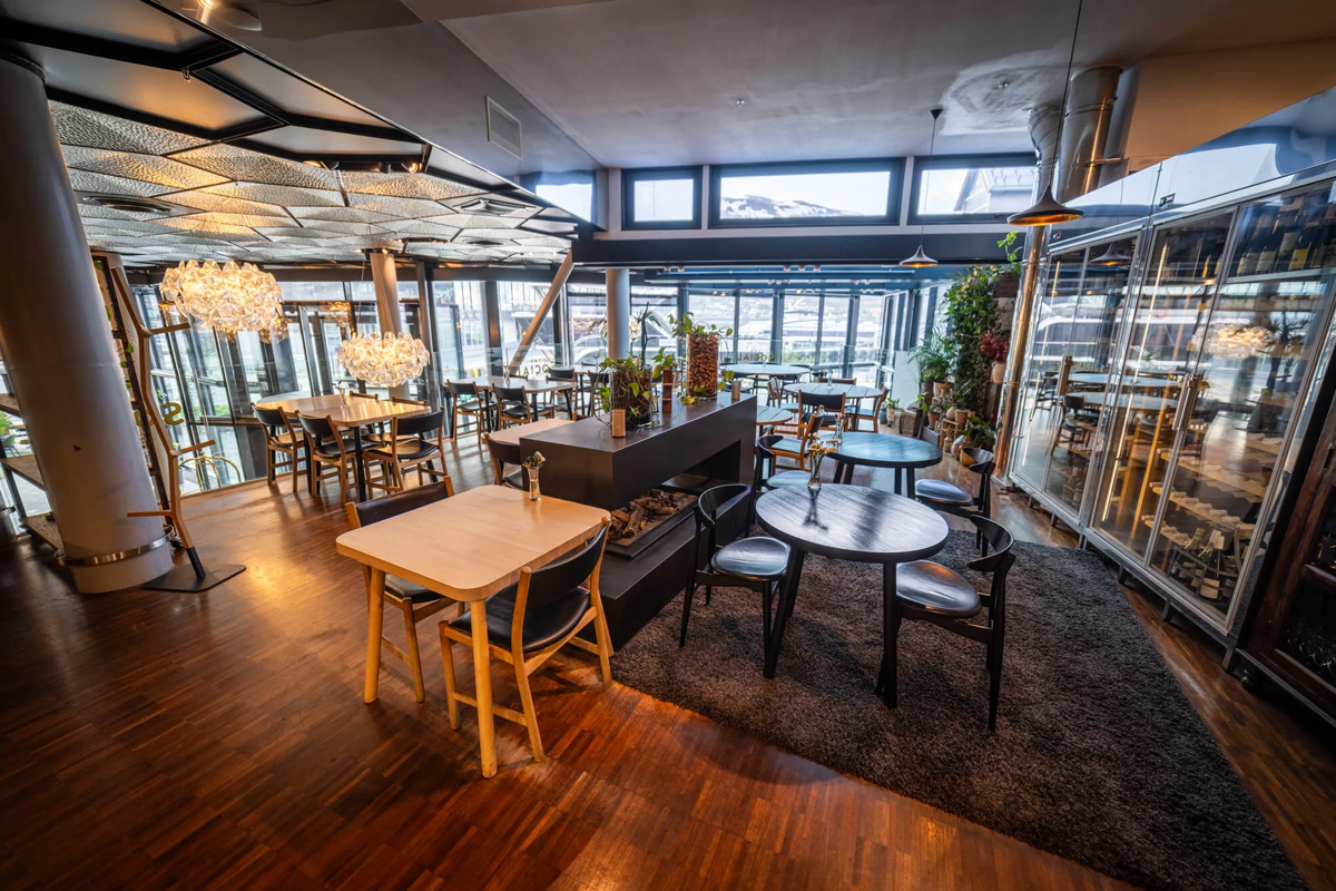 The wood-floored restaurant area with a central fireplace at Clarion Hotel The Edge, Tromso.