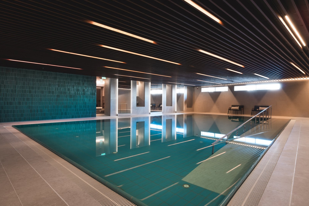 Main indoor pool at St. Elisabeth Hotel & Spa in Tromso, with dark wood ceiling and teal tiles.