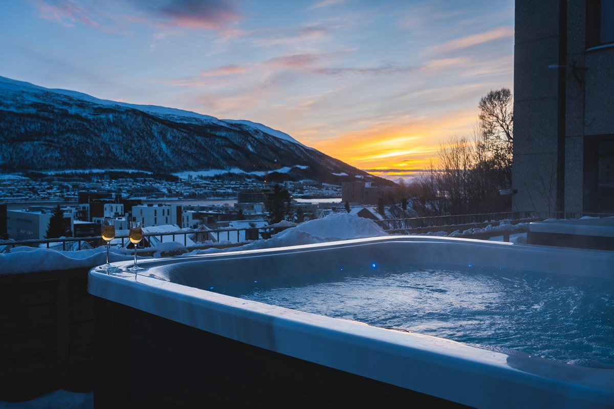 Outdoor jacuzzi at St. Elisabeth Hotel & Spa in Tromso, overlooking the water at sunset.