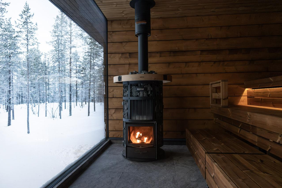 Wood burning stove inside the sauna at Gáldu Spa, with forest view.