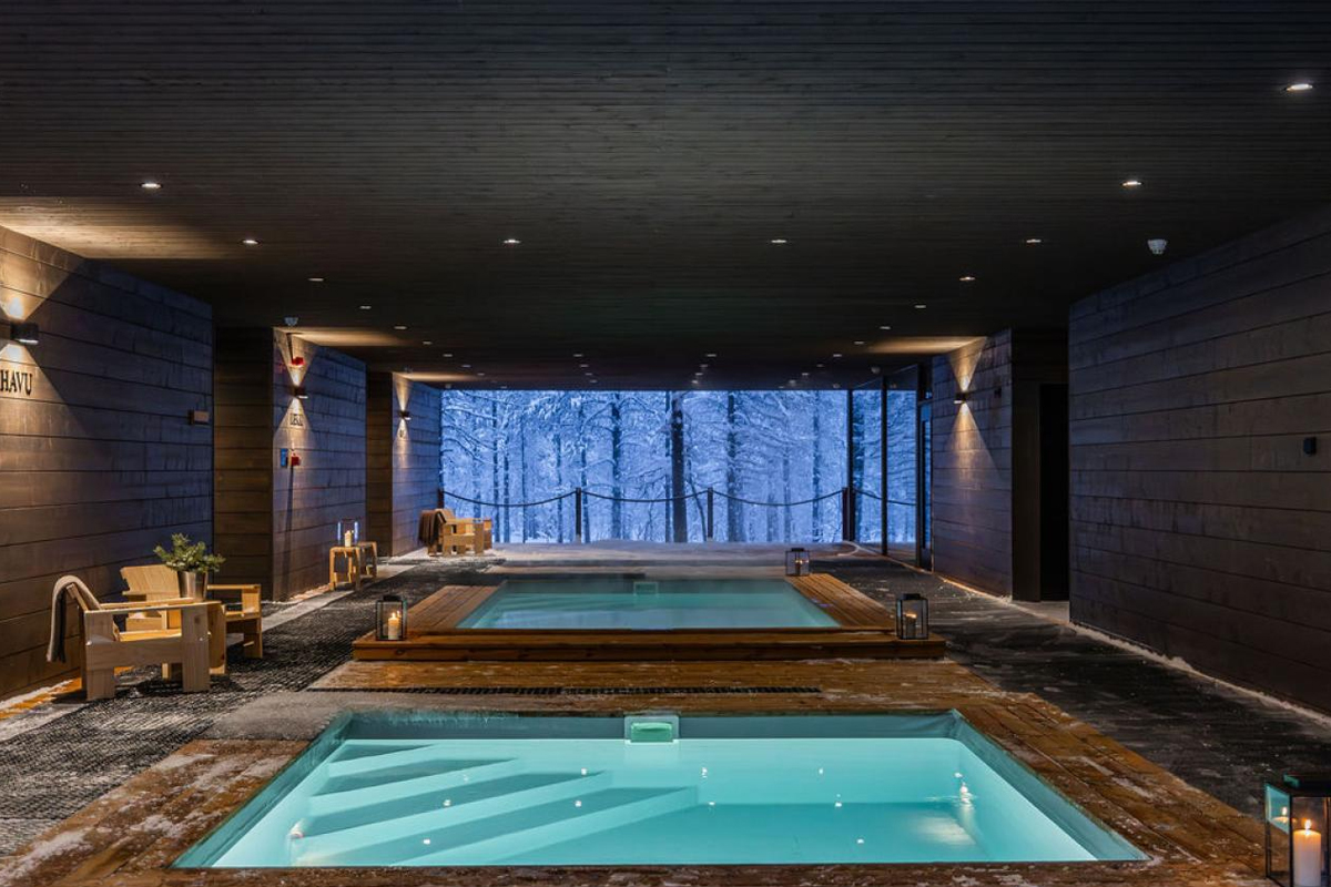 Indoor plunge pools at Gáldu Spa, framed by dark wood and forest views.