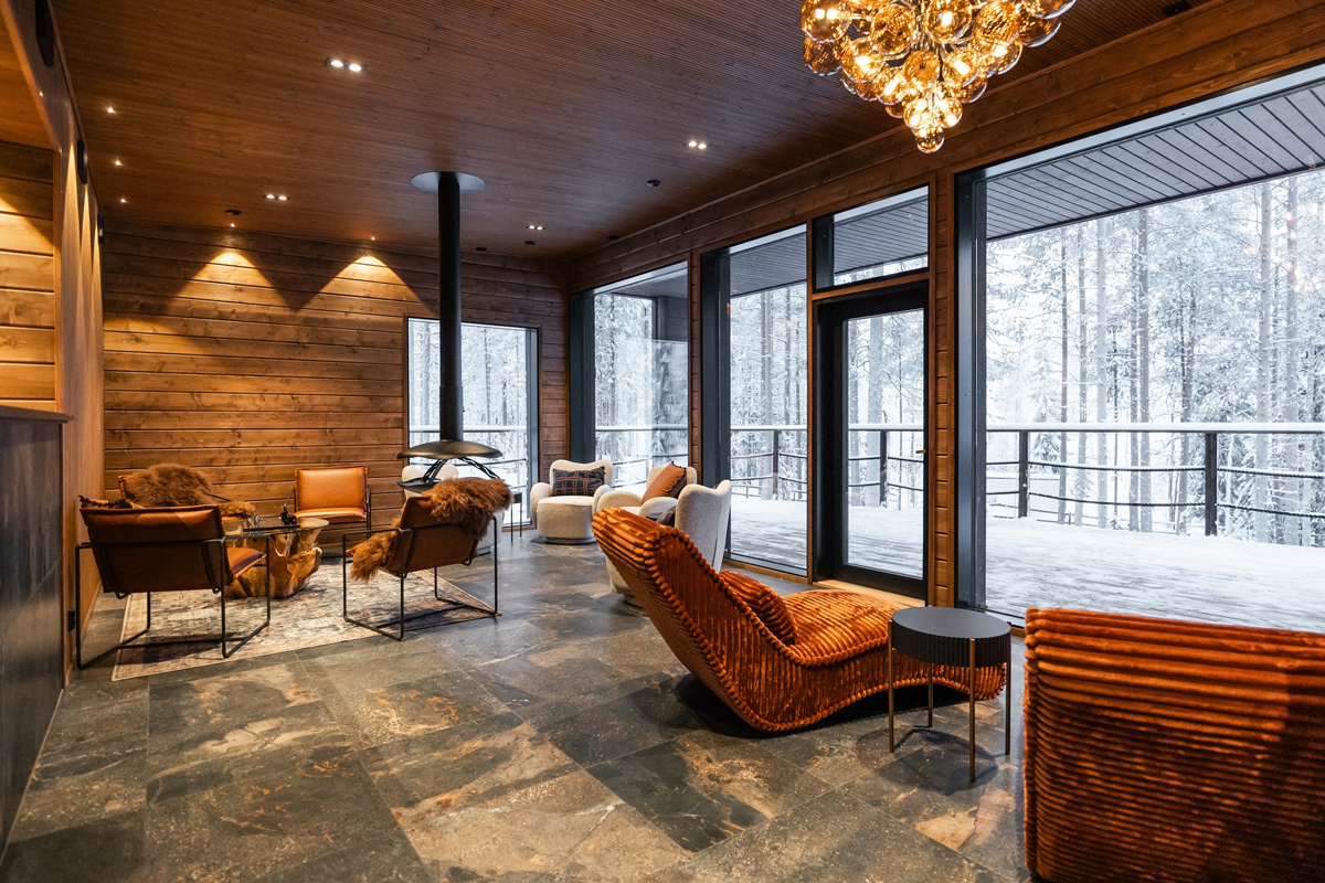 Lounge area at Skyra Retreat, with fireplace and floor to ceiling forest views.
