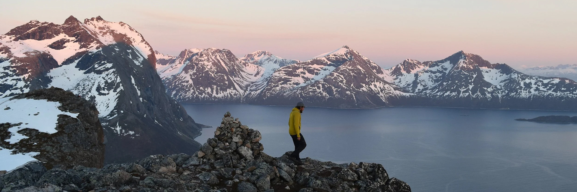 Hiker on a mountain ridge overlooking a fjord at sunset. Photo: Northern Soul Adventures.