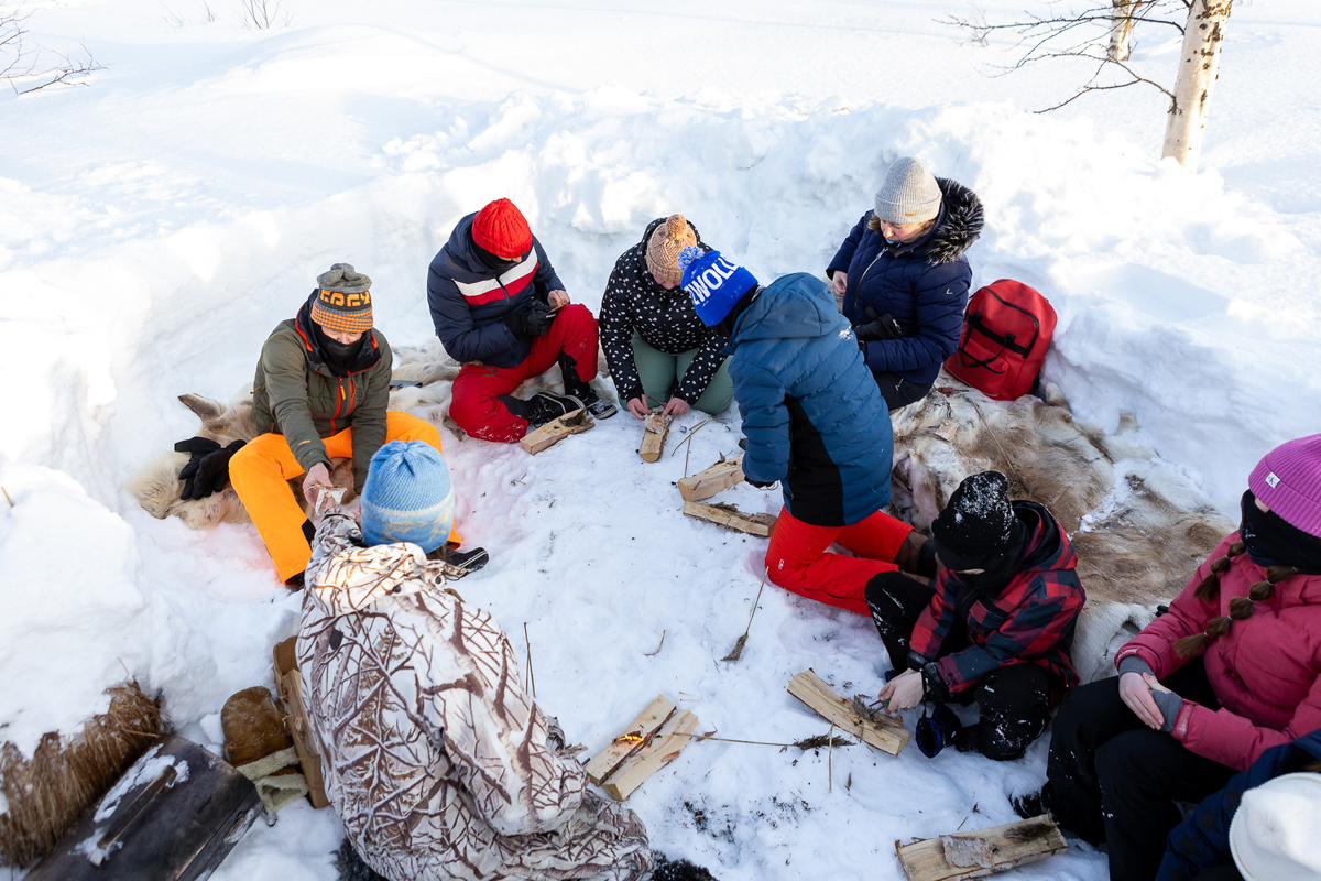 Group learning arctic bushcraft skills in the snow in Lapland