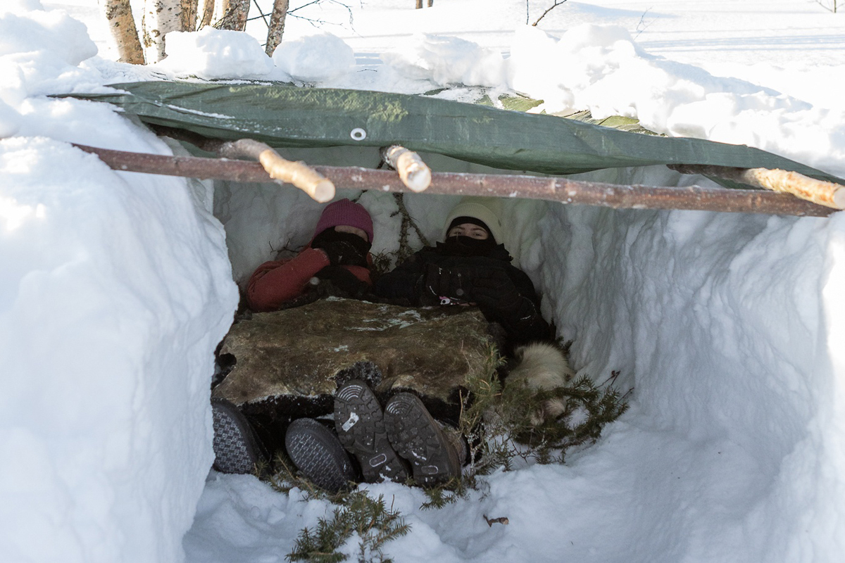 Couple sleeping in a snow shelter during a bushcraft course in Lapland