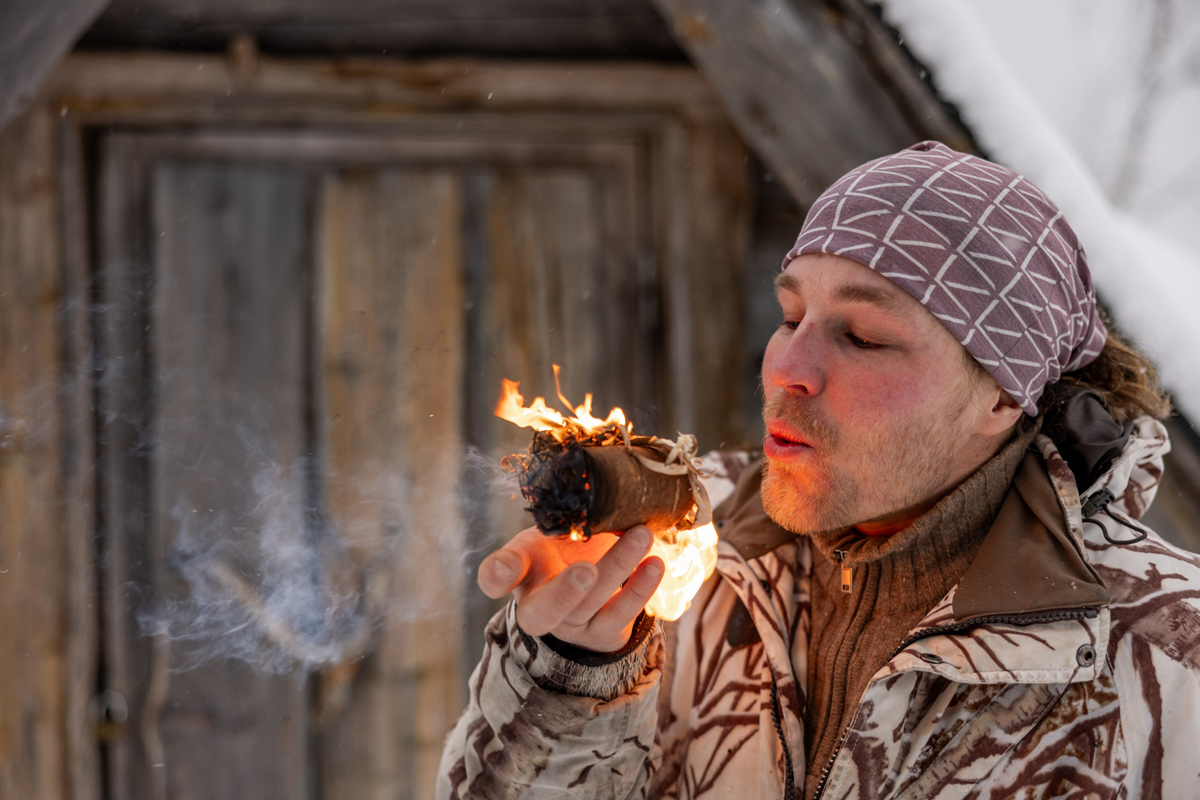 Man blowing on glowing embers during arctic bushcraft course