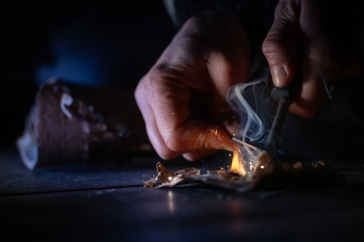 Hands using a fire starter during a buschraft course in Lapland