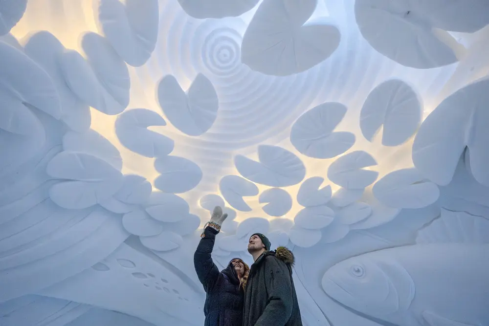 Couple admiring the snow and ice sculptures of the arctic snow hotel in Rovaniemi, Lapland