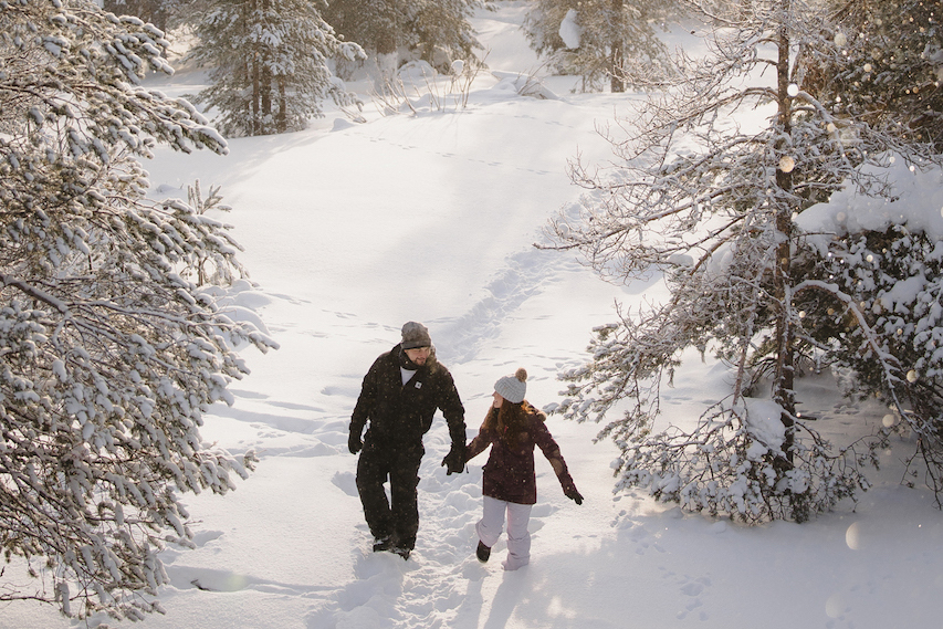 Couple walking hand in hand through a snowy forest in Finnish Lapland  Image 5