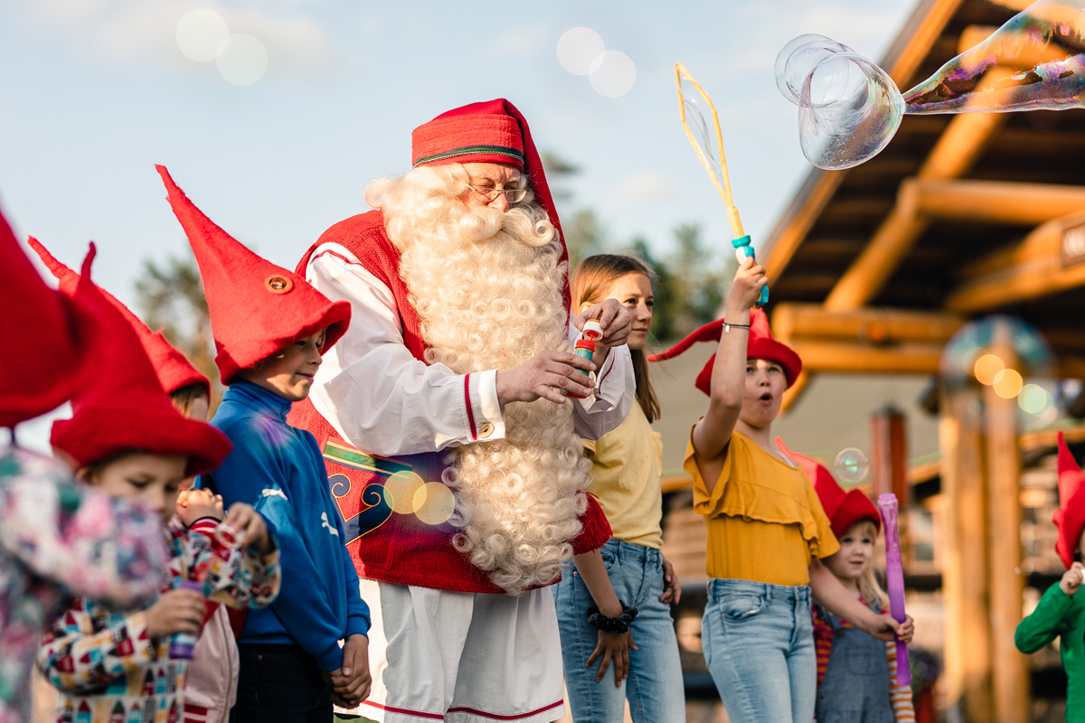 Santa Claus with children in red elf hats and soap bubbles at Santa Claus Village in Rovaniemi