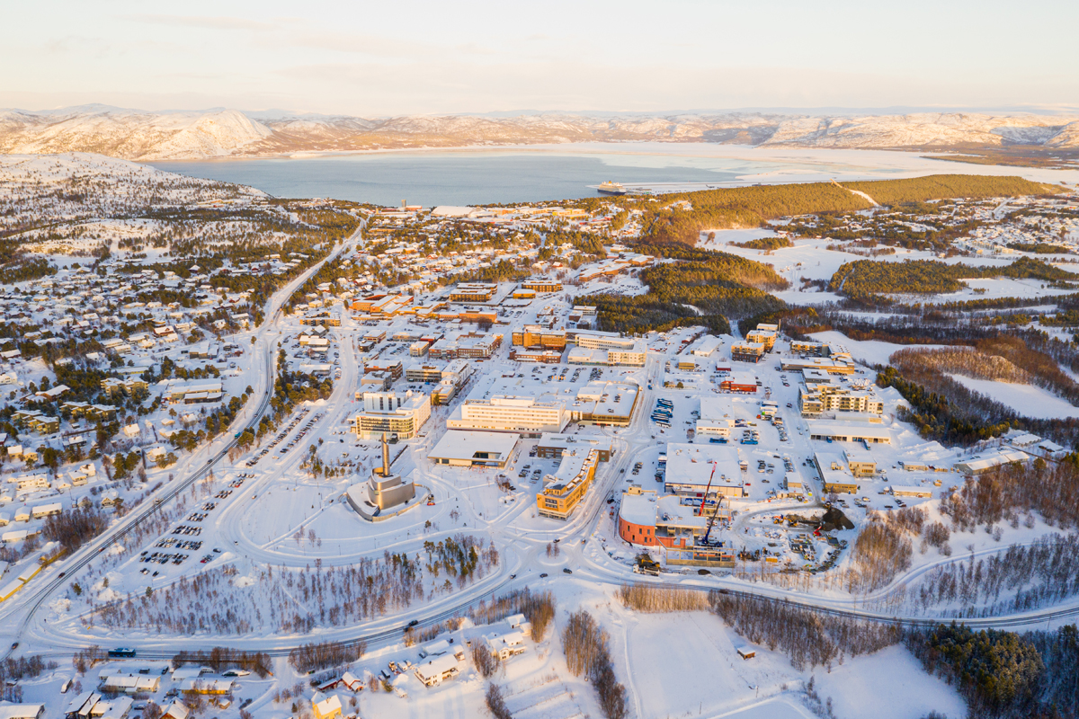 Aerial view of Alta town center and fjord surrounded by snow-covered hills.