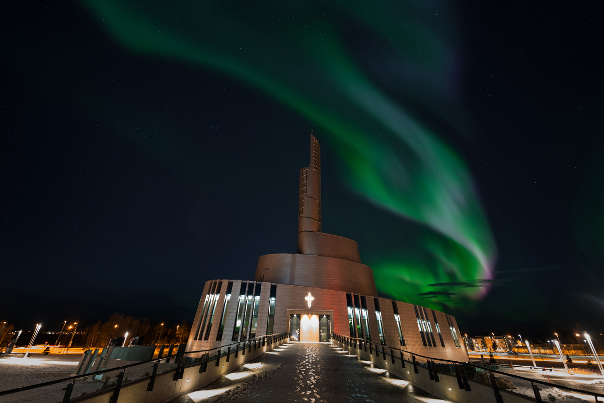 Northern lights swirl above the Northern Lights Cathedral in Alta at night.