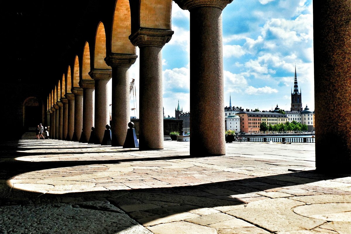 Colonnaded arcade of Stockholm City Hall with a view across the water to the spires of Gamla Stan.