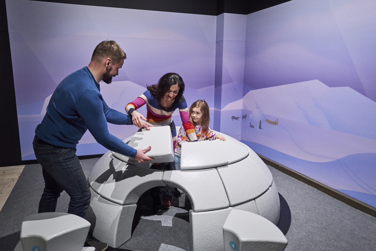 Family exploring an interactive Arctic exhibit at the Arktikum museum in Rovaniemi.