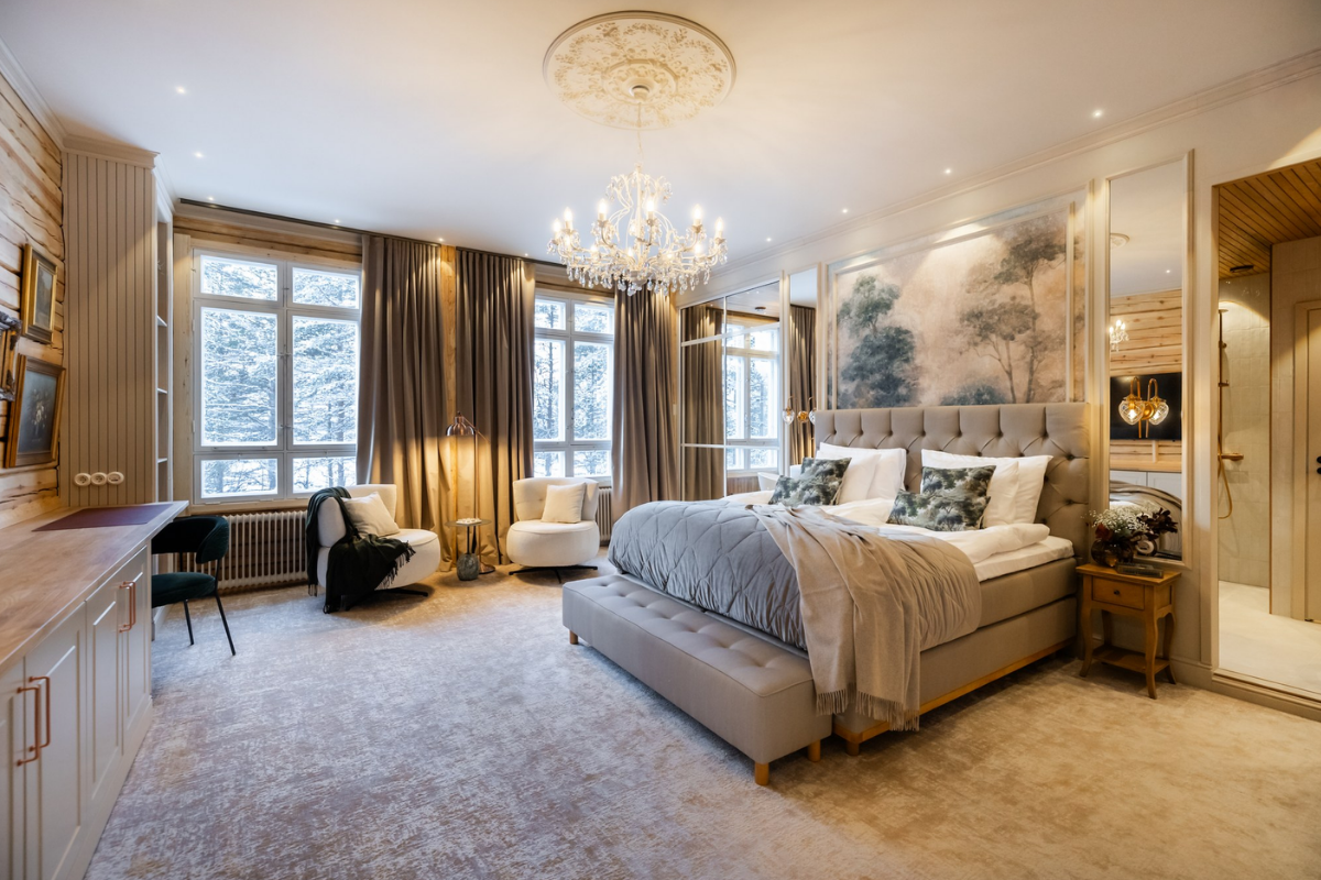 Une chambre suite avec lustre et vue sur la forêt.