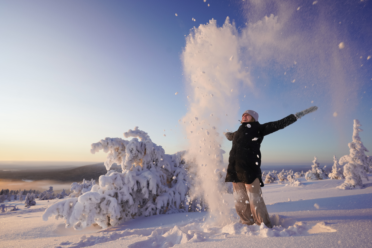 Une femme lançant de la neige poudreuse au sommet d'un fjell, à Levi.