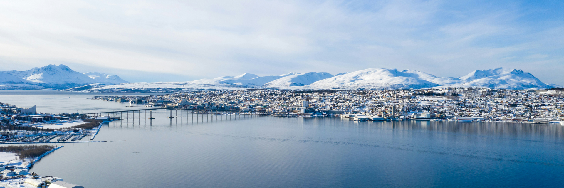 Aerial view of Tromso and its fjord, surrounded by snow capped mountains. Photo: Anton Lammert.