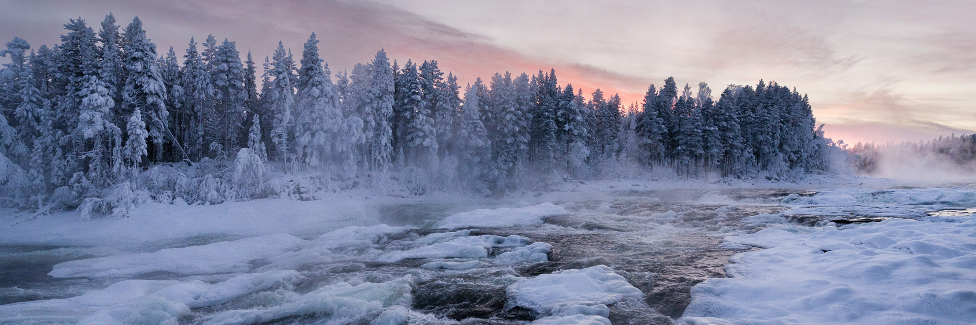 Frozen river winding through a snow covered forest in Swedish Lapland at dusk. Photo: Christoph Nolte.