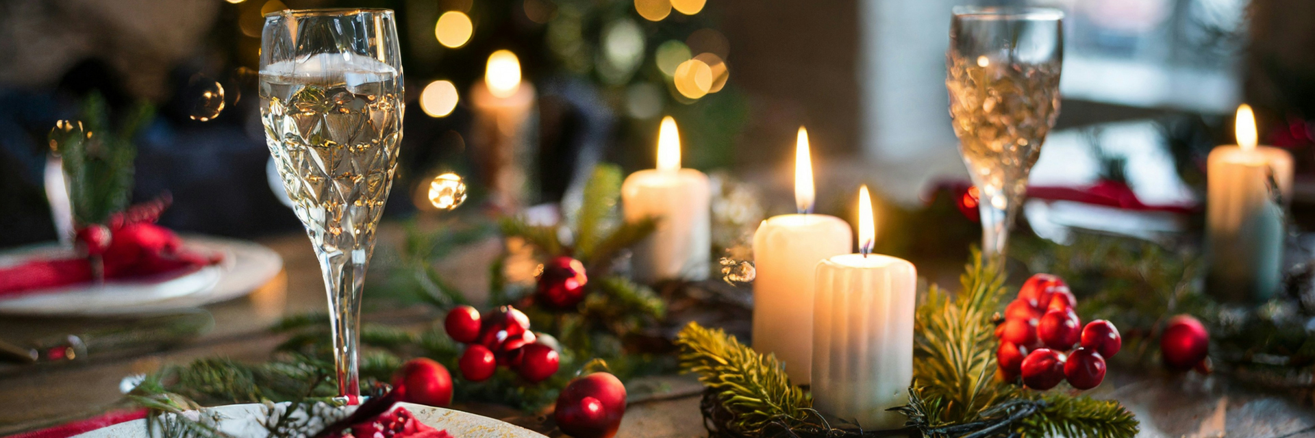 Festive dinner table with champagne flutes, lit candles, pine branches and red berry decorations, Pyhä, Finnish Lapland