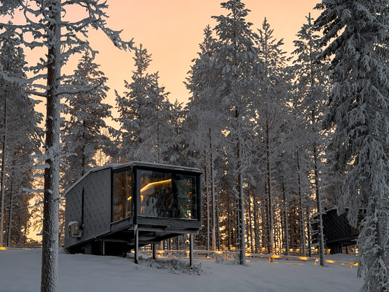 Lumo Resort glass-fronted room among snow-covered trees at dusk in Ruka-Kuusamo.