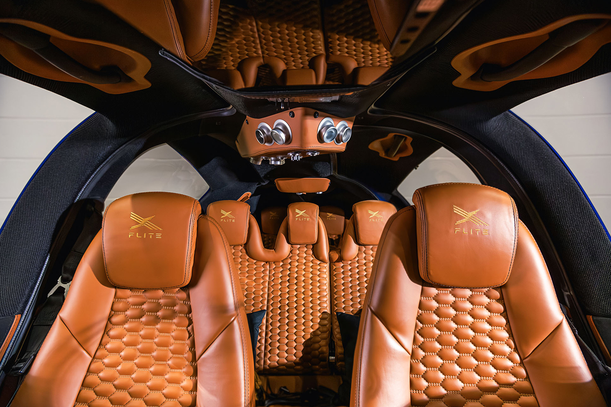Cabine de l'avion privé X-Flite avec sièges en cuir camel matelassé et logo doré